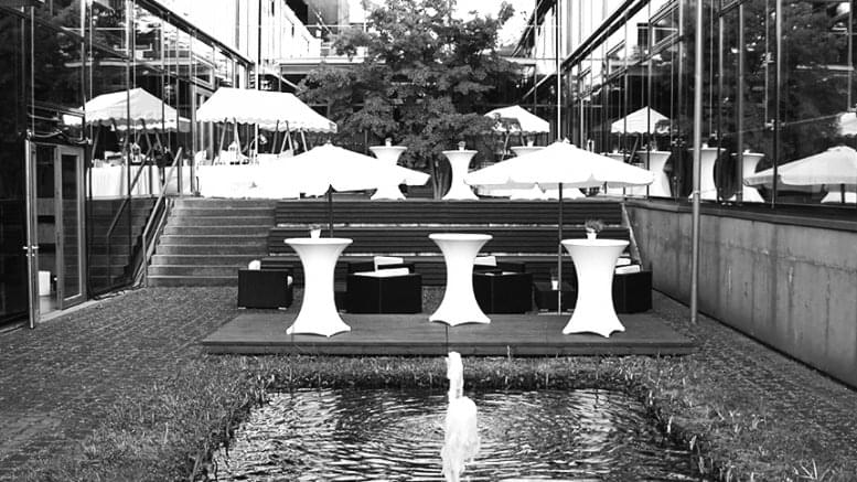 Lichthof mit kl. Springbrunnen, Cocktailtischen und Lounge-Sesseln