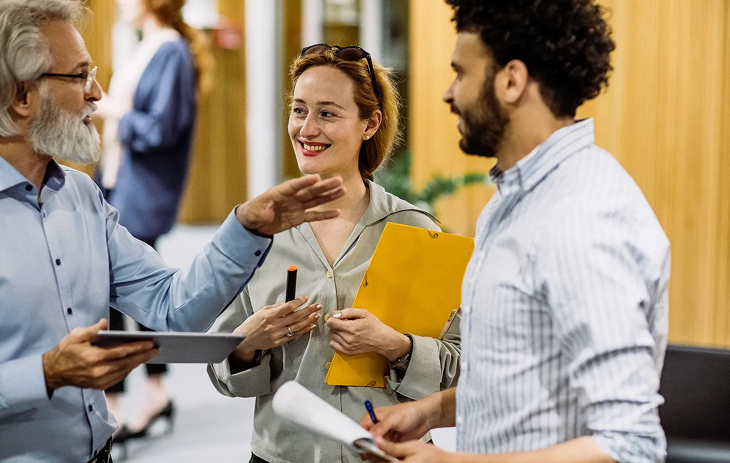 Ein älterer Mann gestikuliert mit links im Gespräch mit einer jungen Frau und Mann.